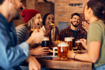 Cheerful friends have fun together while gathering in pub.