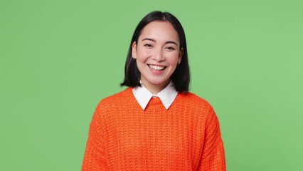 Wall Mural - Beautiful happy cheerful fun young woman of Asian ethnicity 20s she wear knitted orange sweater posing looking camera smiling isolated on plain pastel light green color wall background studio portrait