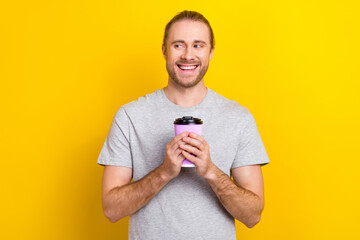 Canvas Print - Photo of cheerful dreamy man wear grey t-shirt drinking tea looking empty space isolated yellow color background