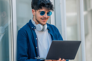 Wall Mural - young man with laptop and sunglasses in the street