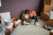 © Seventyfour - High angle view of multiethnic young couple using laptop together while sitting on the floor among boxes