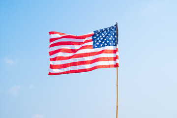 United States of America national flag blowing in the wind isolated for 4th of July or Independence Day. Official patriotic design. Waving sign with blue sky.