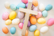 Wood cross on a background of pastel easter eggs