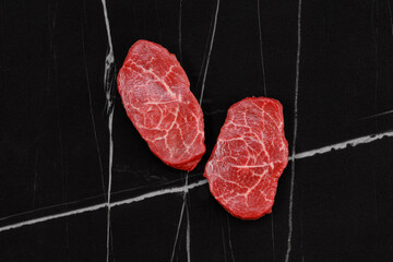 Wall Mural - Raw beef marbled fillet steaks on black marble background, top view. Wagyu fillet. 