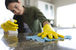 © Wavebreak Media - Caucasian young woman wearing yellow washing up gloves cleaning kitchen counter at home