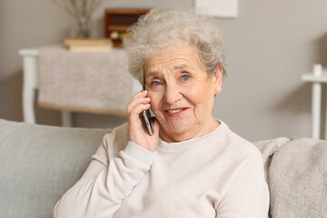 Poster - Senior woman talking by mobile phone on sofa at home, closeup