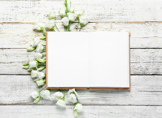 Wall Mural - Composition with blank open book and beautiful eustoma flowers on light wooden background