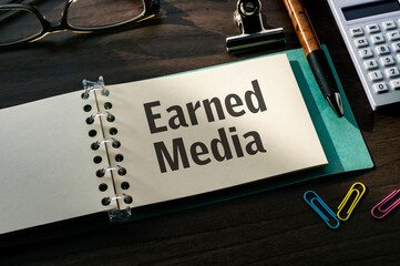 Poster - There is a notebook with the word Earned Media. It is eye-catching image.