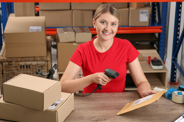 Canvas Print - Post office worker with scanner reading parcel barcode at counter indoors