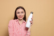 © New Africa - Beautiful young woman with thermos bottle on beige background, space for text