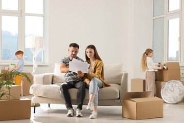 Canvas Print - Family settling into home. Wife with husband choosing interior details while children unpacking boxes in new apartment. Moving day