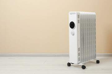 Wall Mural - Modern portable electric heater on floor near beige wall indoors, space for text