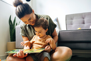 mom reading a book with baby boy at home. early age children education, development. mother and chil