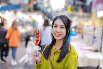 Wall Mural - Woman hold with Tanghulu traditional Chinese hard caramel coated strawberry skewer at street market