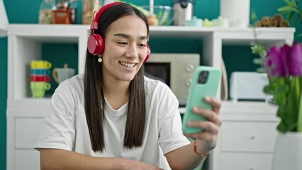 Wall Mural - Young beautiful hispanic woman having video call sitting on table at dinning room