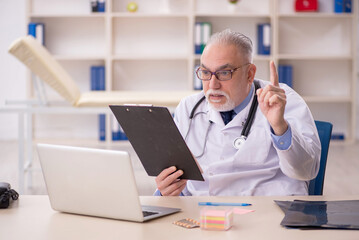 Old male doctor working in the clinic