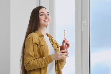 Sticker - Beautiful young woman with delicious smoothie near window indoors. Space for text