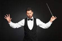 Professional Conductor With Baton On Black Background