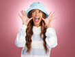 Excited, comic hands and face of woman on studio background for funny, humour and emoji reaction. Beauty, fashion and happy girl model with facial expression in trendy style, cosmetics and casual hat