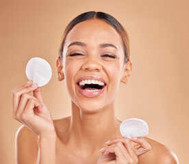 Canvas Print - Face, funny and woman with cotton pad, skincare and happiness against a brown studio background. Portrait female and lady laughing, makeup remover and foundation with smile, dermatology and grooming