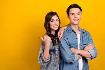 Poster - Portrait of two positive partners embrace toothy smile crossed arms direct finger empty space isolated on yellow color background