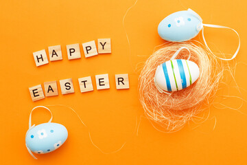 colorful handmade painted eggs in the nest on orange background