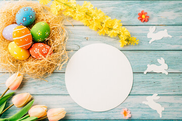 Wall Mural - Happy Easter Day Concept. Flat lay of holiday banner background web design easter eggs in brown nest and blank paper circle on blue wooden background with empty copy space, celebration greeting card