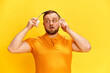 © Lustre Art Group  - One confused man hears strange noise with surprised facial expression over yellow background