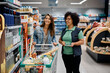 © Drazen - Happy female worker talks to young woman who is shopping at supermarket.