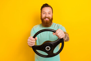 Photo of young brutal taxi driver man wear green t-shirt hold steering wheel fast speed good road volkswagen auto isolated on yellow color background
