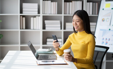 Poster - Young pretty Asian businesswoman using smartphone in the office room, contacting with customer.