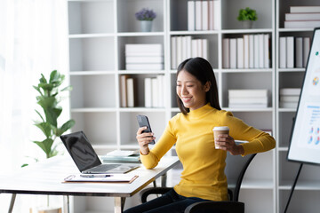 Poster - Young pretty Asian businesswoman using smartphone in the office room, contacting with customer.