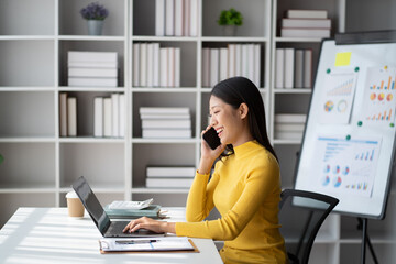 Poster - Young pretty Asian businesswoman using smartphone in the office room, contacting with customer.