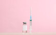 Vaccine bottle with syringe on pink background