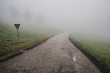 Empty Road Passing By Green Field In Fog