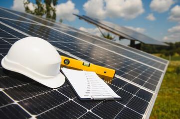 solar cell contractor document with orange engineering team helmet on solar cells panels. renewable 