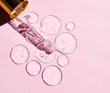 Transparent Drops Of Hyaluronic Acid And Glass Pipette On Pink Background.