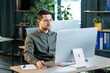 © Ivan - Portrait of young caucasian businessman in casual shirt and glasses using computer computer at workplace