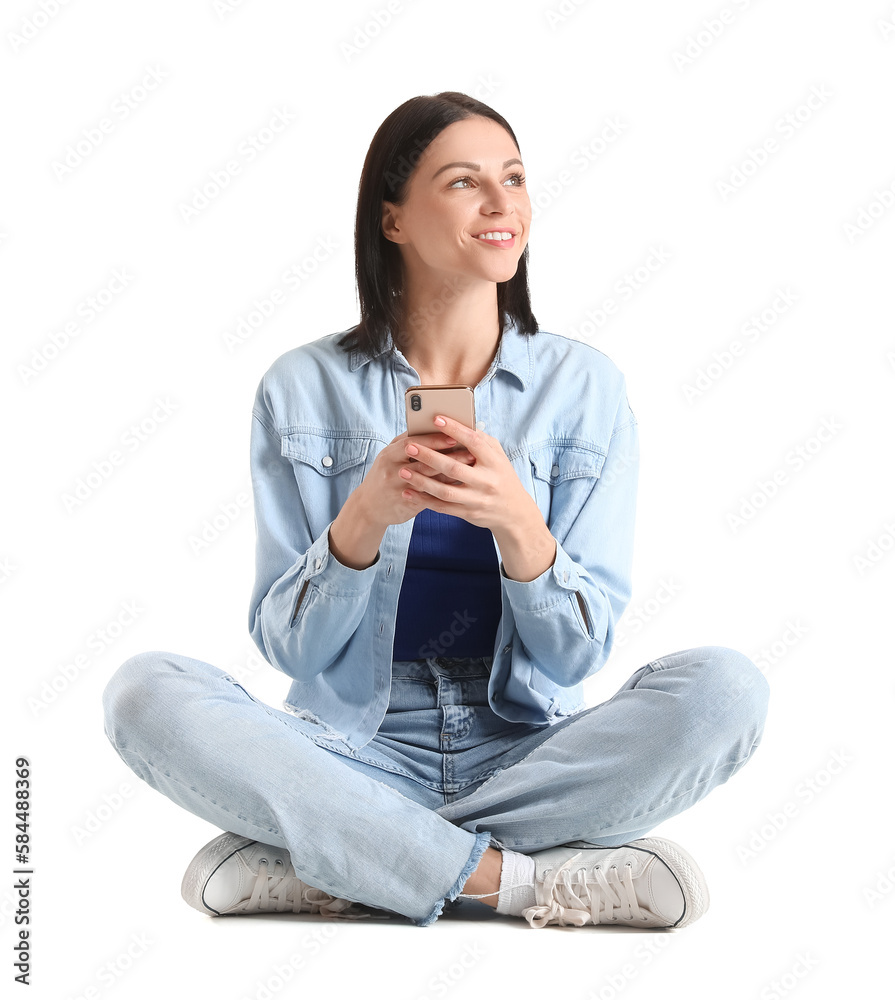 Pretty young woman with smartphone sitting against white background