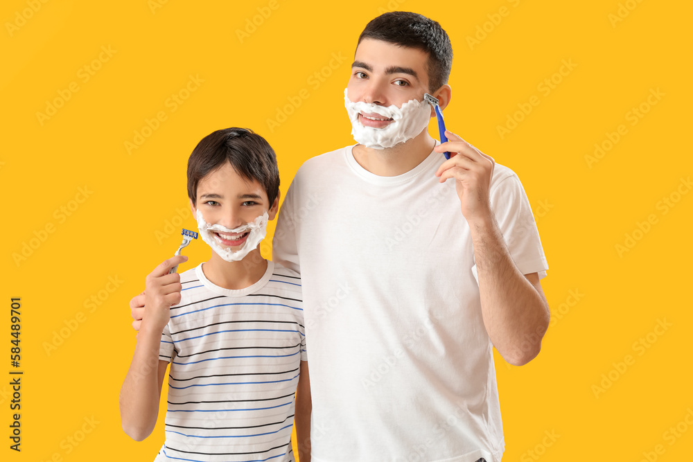 Man and his little son shaving against yellow background