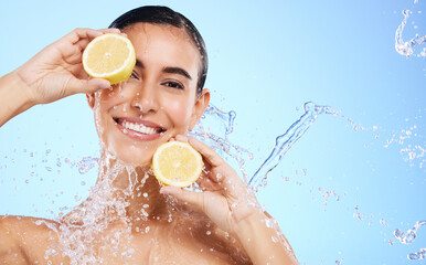 Wall Mural - Beauty, lemon and water splash with portrait of woman in studio for natural cosmetics, nutrition and detox. Glow, fruits and hydration with female on blue background for diet, clean face and skincare