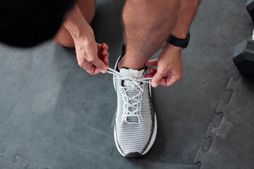 Canvas Print - Top view, hands and tie shoes in gym to start workout, training or exercise for sports. Athlete, man and tying laces on sneakers to prepare for running, cardio or exercising for health or fitness.