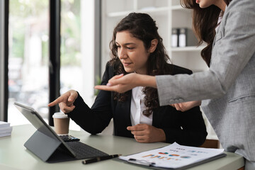 Wall Mural - Two smart multiethnic business people working together with laptop while working on project in office