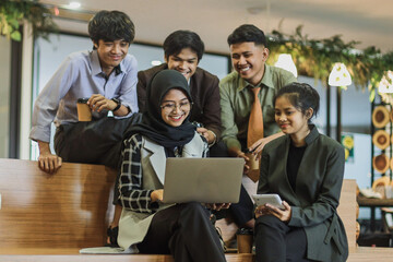 Smiling multiethnic employees discuss share ideas using laptop at creative office space. Collaboration concept. 