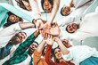 © Davide Angelini - Multicultural group of people stacking hands together - University students putting their hands on top of each other - Human relationship, social, community, startup, teambuilding and college concept