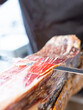 photo detail of a knife cutting serrano ham