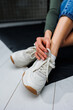 © DSMT - Sports shoes for women. Slender female legs in jeans and white stylish casual sneakers. Women's comfortable summer shoes. Casual women's fashion