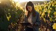 © nenetus - Wine grower woman watching the growth of the grape crop while taking notes on the tablet in the vineyard. Generative Ai