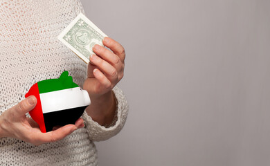 Flag of United Arab Emirates on money bank in UAE woman hands. Dotations, pension fund, poverty, wealth, retirement concept