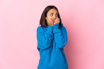 Wall Mural - Young latin woman isolated on pink background nervous and scared putting hands to mouth